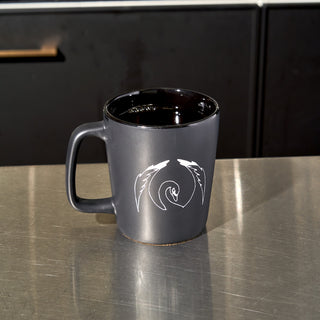 Black ceramic coffee mug with a swan graphic.