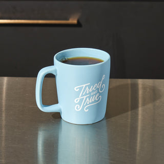 Blue ceramic coffee mug with a tried and true script graphic.