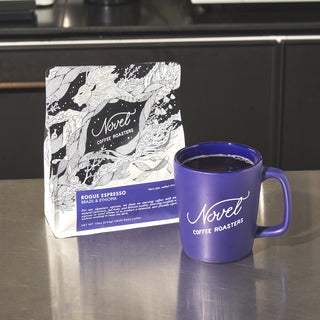 10 oz bag of rogue espresso next to a purple branded ceramic mug.