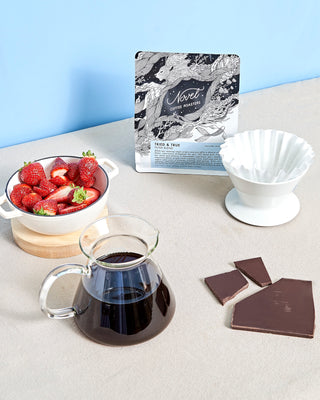 Tried & True Filter blend coffee at a breakfast table with a bowl of strawberries and an unwrapped chocolate bar.